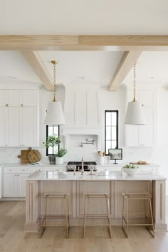 a large kitchen with white cabinets and wooden beams on the ceiling, along with stools