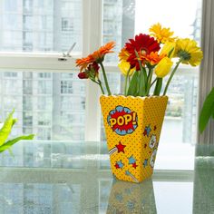 a vase filled with colorful flowers sitting on top of a table next to a window