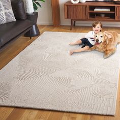 a young boy and his dog are sitting on the floor in front of a rug