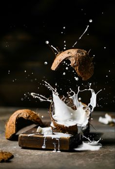 a piece of coconut falling into milk and splashing it on to the ground,