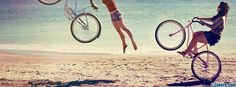 two women riding bikes on the beach while another woman is hanging upside down in the air