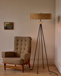 a chair sitting next to a lamp on top of a hard wood floor near a wall