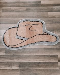 a bathroom rug with a cowboy hat on the floor in front of wood planks