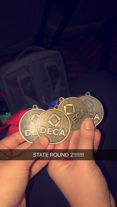 someone is holding two medals in their hand with the word bcdeca on it