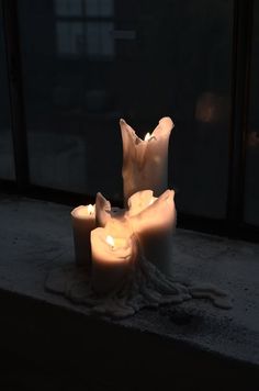 three lit candles sitting on top of a window sill