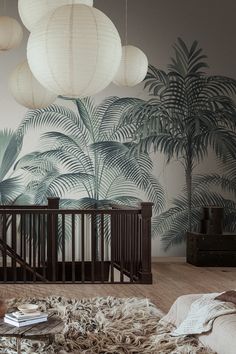 a baby's room with palm tree wallpaper and hanging lanterns above the crib