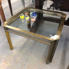 a table with glass top and metal legs in a room filled with chairs, tables and other furniture