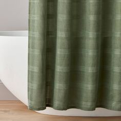 a bath tub sitting next to a shower curtain with a green checkered pattern on it