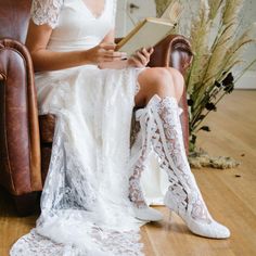 a woman is sitting in a chair with her legs crossed and holding a book while wearing white lace garters