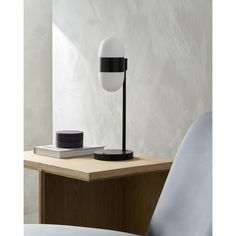 a black and white lamp sitting on top of a wooden table next to a chair