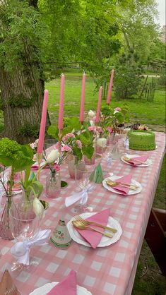 the table is set with pink and white napkins, silverware, candles, and flowers