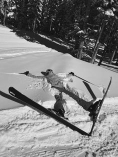 a man riding skis down the side of a snow covered slope with trees in the background