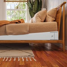 a bed sitting on top of a hard wood floor next to a potted plant