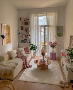 a living room filled with furniture and a large window covered in white curtained drapes