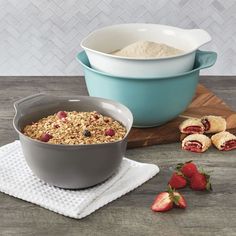 a bowl of oatmeal and some strawberries on a wooden table next to it