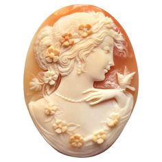 a white and orange brooch with a woman's face in profile, surrounded by flowers