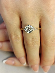 a woman's hand with a diamond ring on top of her finger and the other hand holding an engagement ring