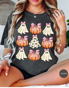 Add a touch of sweet spookiness to your Halloween wardrobe with our Boo-tiful Ghostly Charm Tee! This enchanting shirt showcases adorable ghosts adorned with pink bows, playfully floating amidst a patch of pumpkins. Perfect for Halloween festivities, cozy autumn days, or just embracing the fall spirit, this tee combines cuteness with a hint of haunt. Get ready to delight in the season with this charmingly spooky design! Halloween Cricket Shirts, Halloween T Shirt Design, Cute Halloween Shirts, Cute Halloween Graphic Print T-shirt, Halloween Shirts, Pink Cotton T-shirt For Halloween, Casual Halloween T-shirt With Sublimation Print, Pink Halloween T-shirt With Character Print, Halloween Character Print Relaxed T-shirt