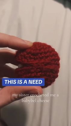 someone is holding up a crocheted red piece of yarn that says, this is a need