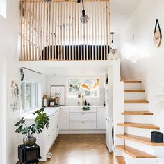 a kitchen with white cabinets and wooden stairs