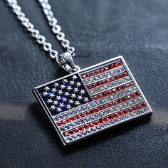 an american flag pendant is shown on a black surface with a chain that has the word america written in red, white and blue