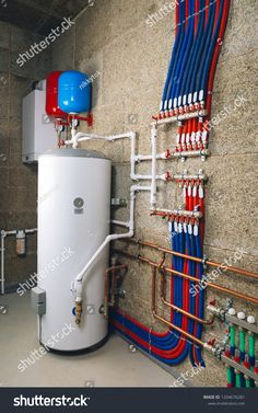 a water heater and pipes in a room with exposed piping lines on the wall