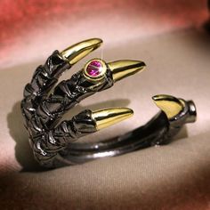 This gorgeously detailed ring depicts a dragon claw, with black and gold IP-plating.Its adjustable open design allows it to fit on different size fingers. A striking accent any dragon or fantasy fan's outfit. Sizing Guide Size Approximate Ring Size Fit (US Ring Sizes) Small 5-7 Medium 7-9 Large 9-12 **Ring sizing/conversion tool.** Materials: Copper, Cubic Zirconia Click ADD TO CART To Order Yours Now! The Checkout Process is Guaranteed to be 100% Safe and Secure with Visa, Mastercard, AMex, Discover, Apple Pay or PayPal. Black Claw-shaped Halloween Jewelry, Black Metal Rings For Halloween, Black Punk Style Open Ring Jewelry, Gothic Claw Shaped Metal Rings, Edgy Adjustable Rings For Halloween, Adjustable Edgy Halloween Rings, Black Fantasy Rings As Gift, Fantasy Style Black Ring For Gift, Black Fantasy Style Rings As Gift