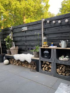 a bench made out of cinder blocks and stacked logs in front of a wooden fence