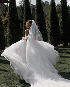 a woman in a wedding dress is sitting on the grass