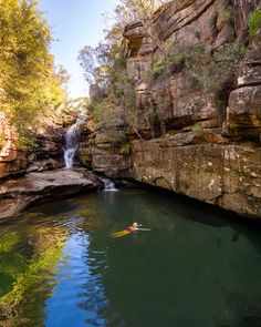 a person in a kayak near a waterfall and some rocks with water running down it