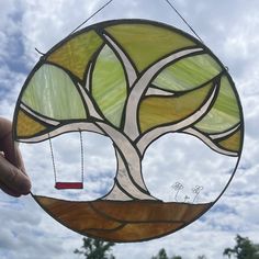 a stained glass window with a swing hanging from it's side and a tree in the middle