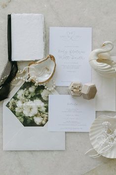 the wedding stationery is laid out on top of each other, including an envelope and ring