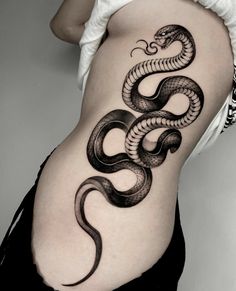 a black and white photo of a woman's stomach with a snake tattoo on it