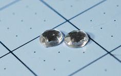 two shiny silver buttons sitting on top of a blue tile floor next to each other