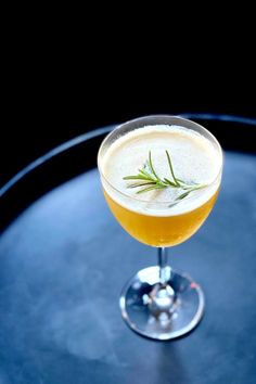 a close up of a drink in a wine glass on a table with a black background