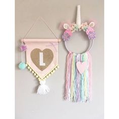 two wall hangings decorated with unicorn ears, hearts and tassels on them