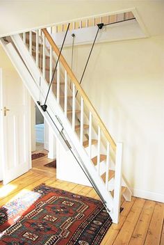 a stair case in an empty room with wood flooring and rug on the ground