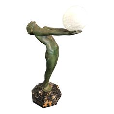 a bronze statue holding a white ball on top of it's back legs and arms