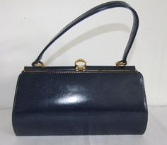 Classic 60s handbag In sheeny blue vinyl Dark blue - appears a little darker in photographs than in life Black lined with inside pocket Gold coloured metal clasp and top Distinctive round shape clasp Generally good vintage condition, some scuffs to base, some imperfections to vinyl Mesaures approx 11" long by 6" tall by 3 3/4" across base (28 x 15 x 9cm) Retro Blue Evening Bags, Blue Retro Evening Bag, Retro Blue Bags For Formal Occasions, Vintage Blue Satchel For Travel, Vintage Blue Travel Satchel, Blue Vintage Travel Satchel, Vintage Blue Rectangular Shoulder Bag, Vintage Blue Shoulder Bag With Detachable Handle, Vintage Blue Satchel