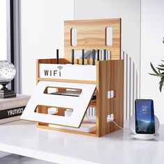 a white table topped with boxes and cell phones next to a plant in a vase