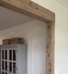 an empty room with white walls and wooden beams on the ceiling, along with a cabinet in the corner