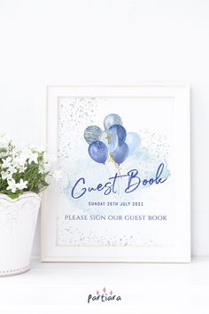 the guest book sign is next to a potted plant on a white shelf with flowers