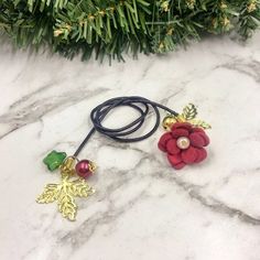 two red flowers on a black cord next to a green christmas tree with gold leaves