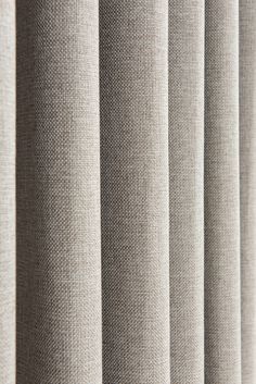 a close up view of a curtain with vertical blinds in beige fabric, which is slightly open