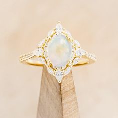 an opal and diamond ring on top of a wooden stand