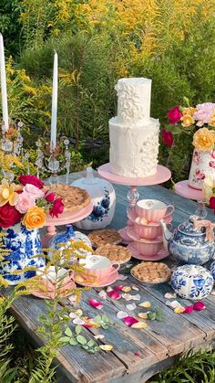 a table topped with lots of different types of cakes and desserts next to flowers