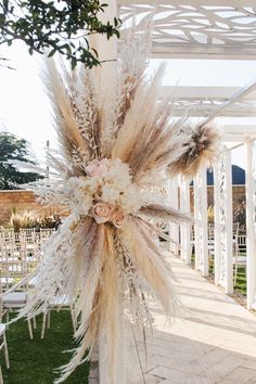 an outdoor wedding venue decorated with pamodia and white flowers in the middle of the aisle