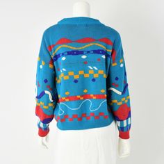 "Turquoise with a multi-colored design & sewn on corded knit decoration. Mock neck. Over-sized fit. Estimated Modern Size: Fits M/L *Vintage clothing runs significantly smaller than modern clothing. We offer a comprehensive size estimation in accordance with modern day size charts. Vintage Tag Size: L Material: acrylic Great vintage with no major flaws to note. Chest: 40\" Shoulder: 23.5\" Sleeve: 19\" Length: 23\" ----------------------------------------------------------------------------- Novelty Sweater, Mom Jeans Shorts, Modern Clothing, High Rise Mom Jeans, Floral Print Skirt, Pullover Sweater Women, High Waisted Shorts Denim, Faux Fur Collar, Modern Outfits