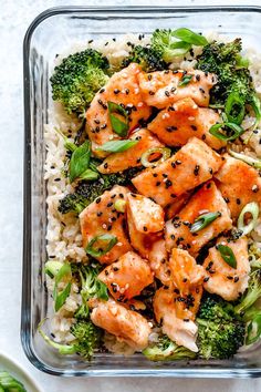 a glass dish filled with rice, broccoli and salmon