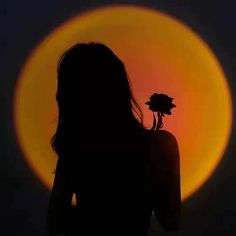 the silhouette of a woman with a flower in her hand